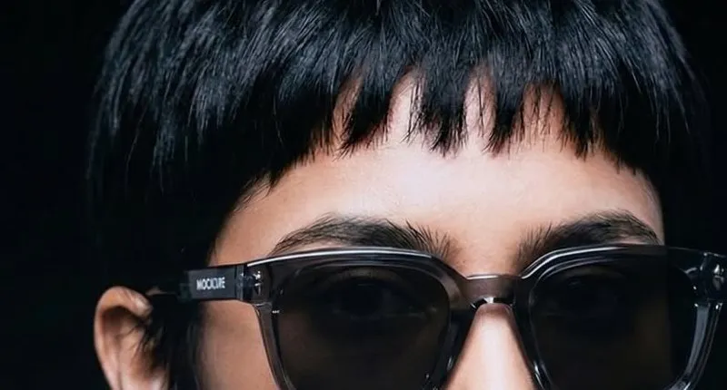 Close view of square smoke-grey sunglasses worn by a model