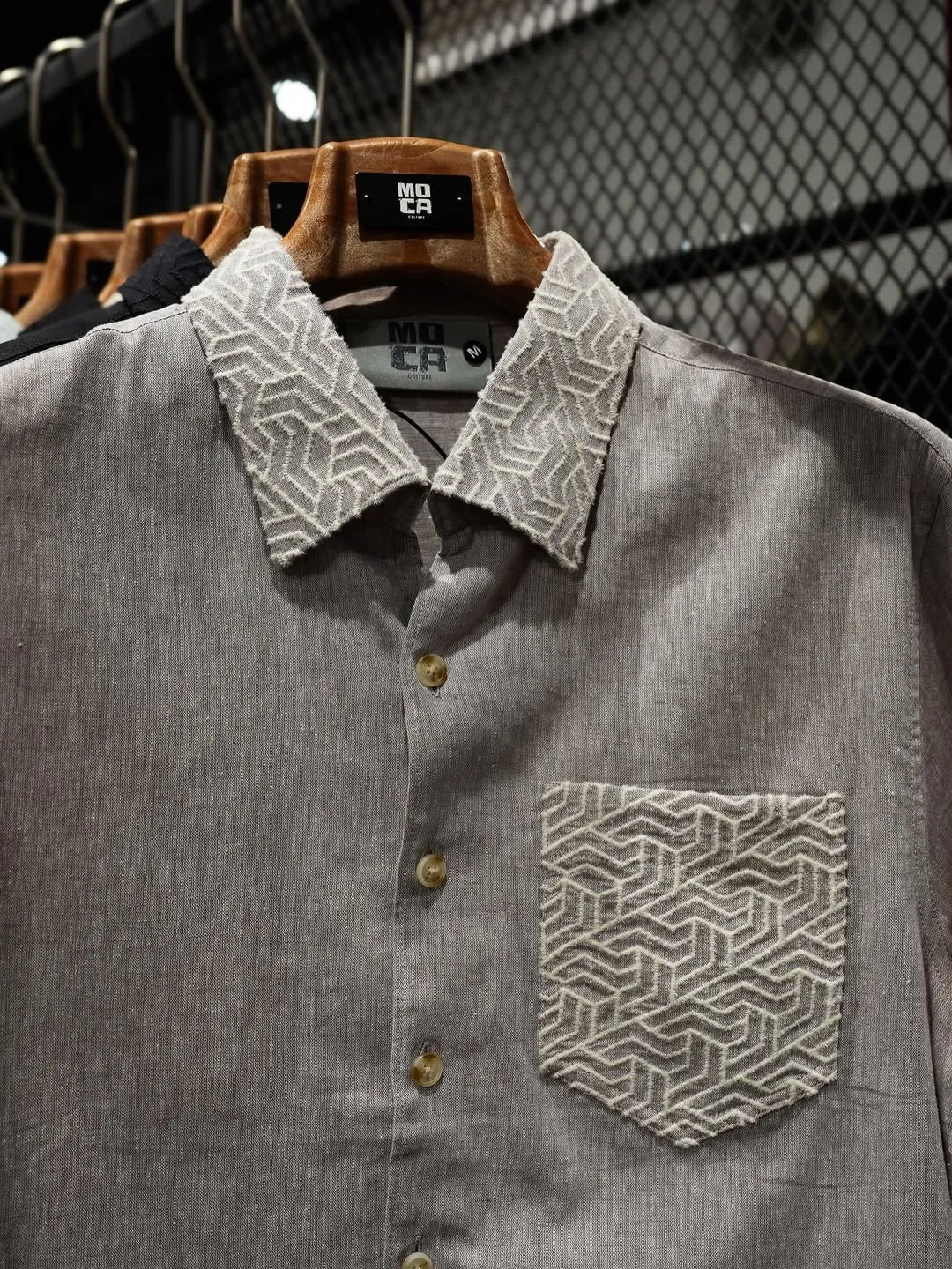 Close view of a taupe linen shirt with a textured geometric collar and pocket