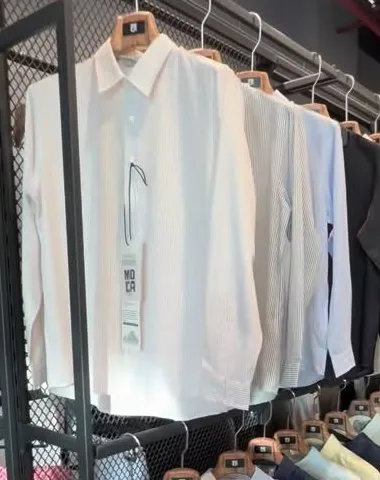 Close view of white and fine-stripe long-sleeve shirts on wooden hangers
